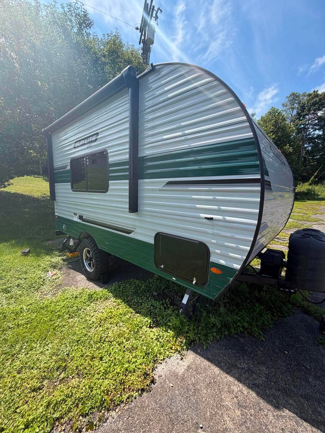 Side view of a green and white "Sun-Lite Sport" travel trailer. Great choice for an rv rental adventure!|This RV rental interior shows a compact kitchen with sink