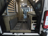 Explore this RV rental's versatile camper van interior: rear view shows a convertible bed, pull-out storage, and utility panel.