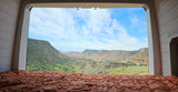 View from an RV rental's bed of a vast, green canyon and distant mountains under a blue sky, ideal for adventurers.