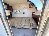 RV rental interior showing a comfortable sleeping area with bed, TV, AC, and a view outside.