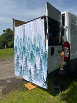 RV rental: Outdoor shower setup with a pine forest curtain, wooden mat, and step stool at the rear of a white camper van.