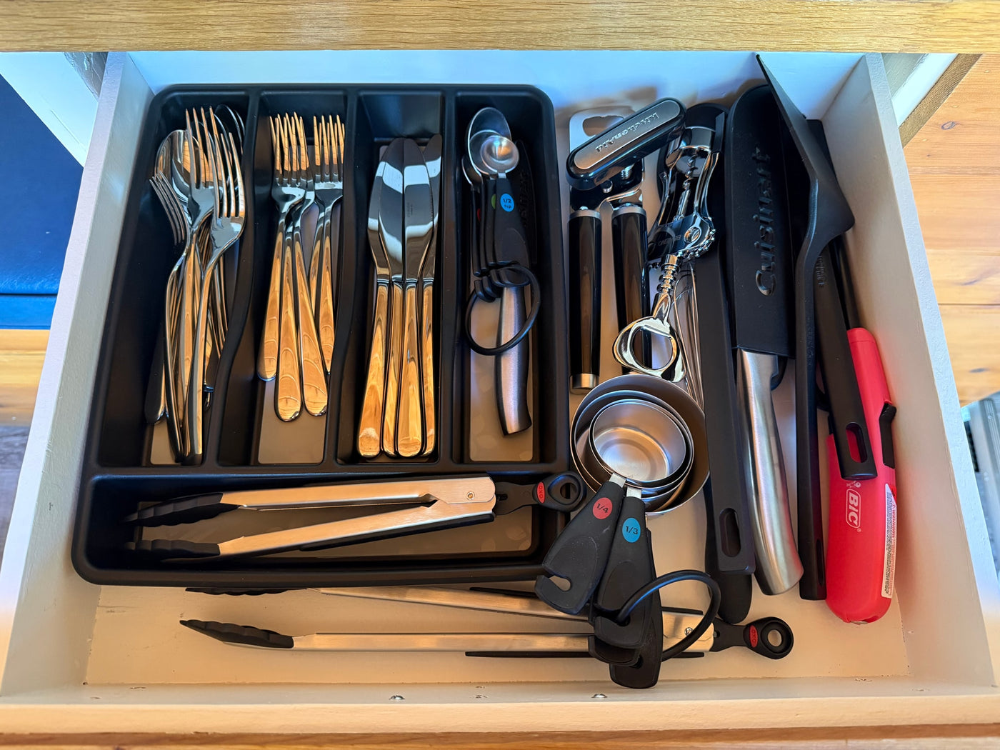 An RV rental kitchen drawer, organized with cutlery, measuring tools, and cooking utensils. — photo 19