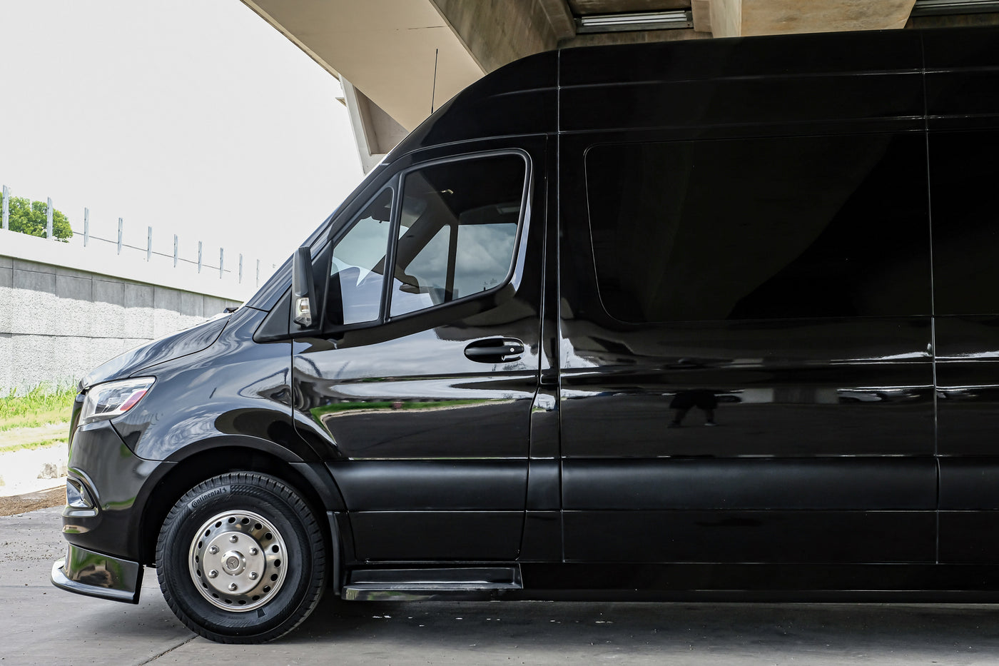 Shiny black Mercedes-Benz Sprinter van, a top choice for your RV rental, parked under an overpass. — photo 14