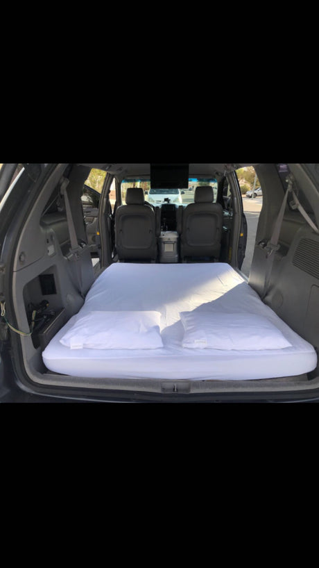Minivan converted into a cozy sleeper with mattress and pillows. Ideal for car camping, a budget-friendly rv rental alternative.