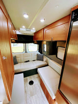 RV rental interior: light wood cabinetry, comfy seating, and windows create a bright living space for touring.