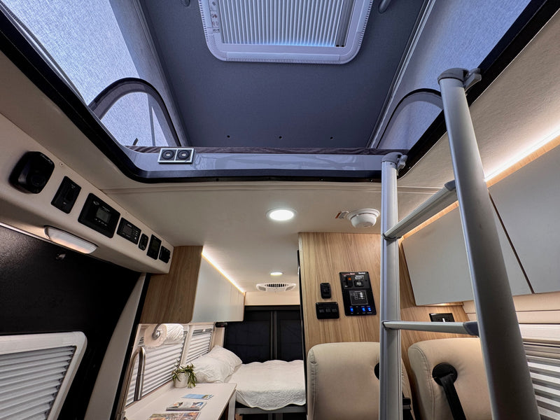 Inside an rv rental: Looking back from the cab at the functional interior, including a bunk bed, ladder, kitchen, and living area. — photo 5