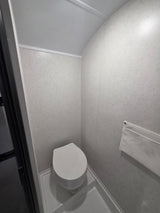  with an awning deployed. Another RV is parked nearby.|RV rental interior: spacious area with wood-look floor