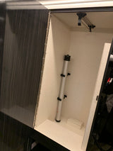 Organized RV rental storage cabinet features a light speckled interior, telescopic pole, and pull-out hanging bar.