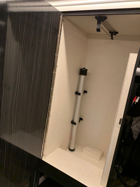 Organized RV rental storage cabinet features a light speckled interior, telescopic pole, and pull-out hanging bar.