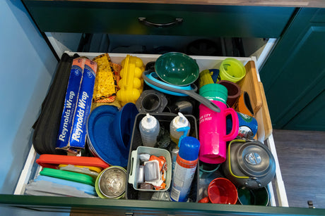 This RV rental drawer is neatly packed with camping kitchen supplies, including foil, plates, and bottles for easy access.