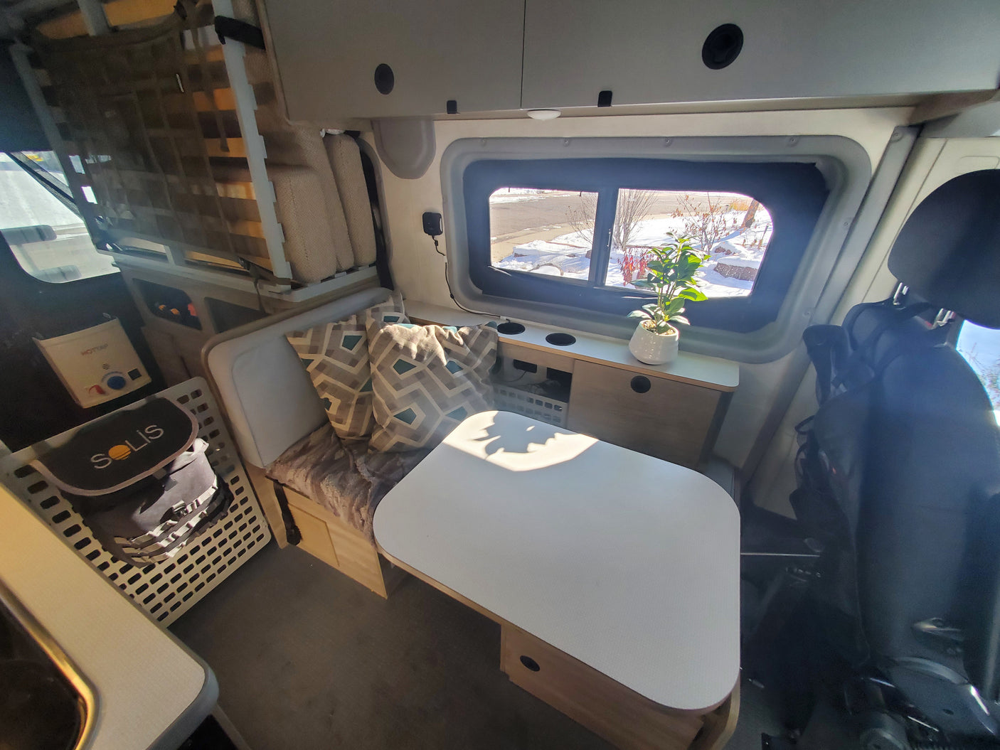 Bright rv rental interior with a cozy dinette, custom storage, and scenic window view for your travels.