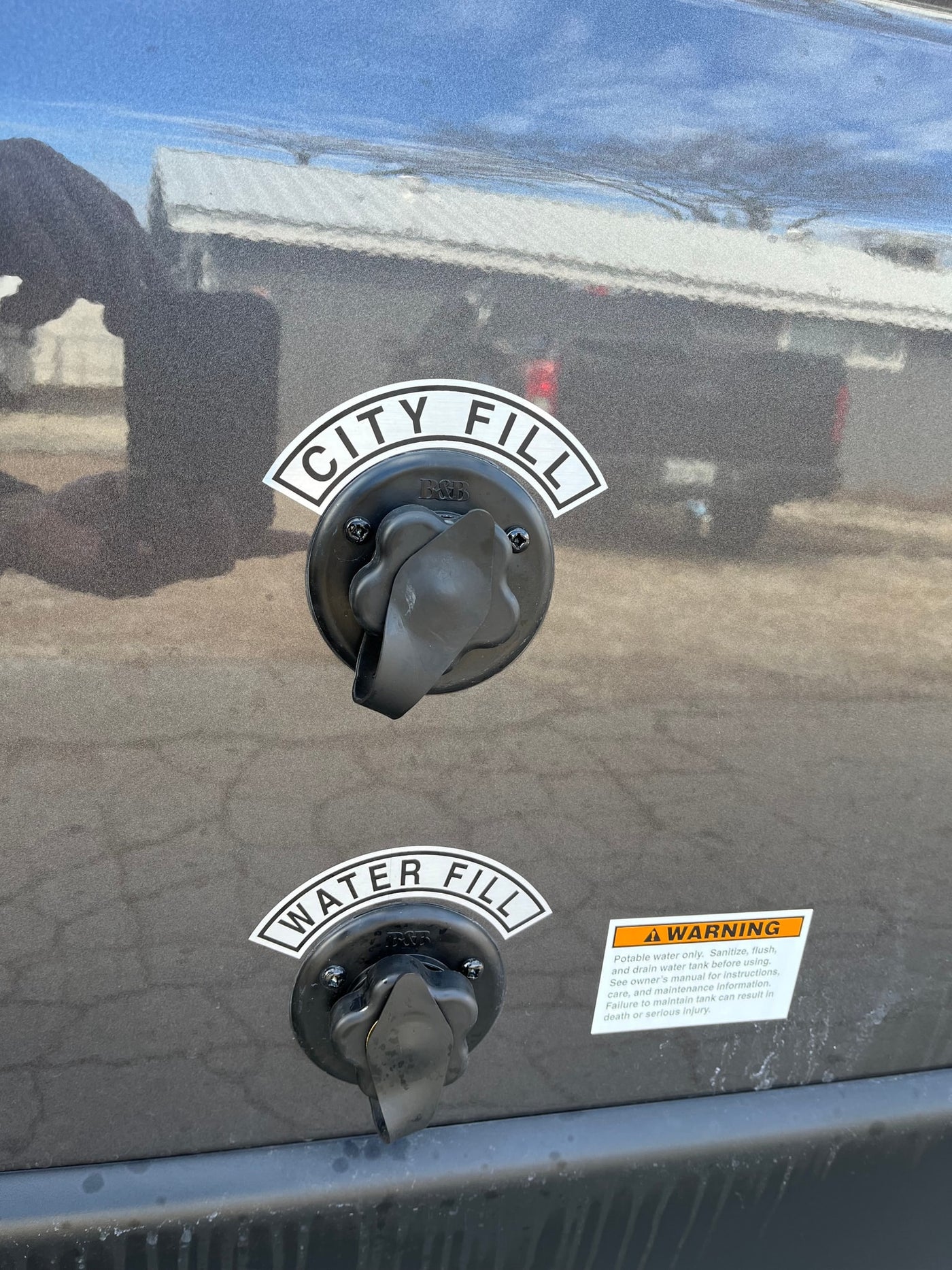 Two water fill ports labeled "CITY FILL" and "WATER FILL" are visible on the side of an RV rental, alongside a safety warning label. — photo 6