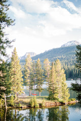 Escape to nature! A red hammock and glamping tent on a lake island, surrounded by forests and mountains. Plan your RV rental getaway.