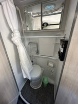 This RV rental features a full, compact bathroom with a toilet, shower, sink, and essential amenities.