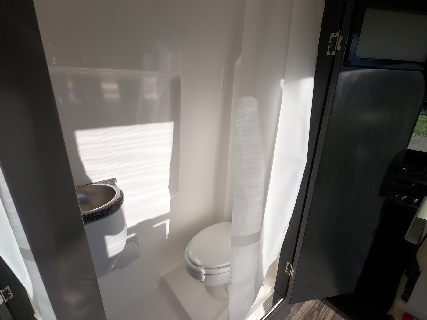 See this bright, compact RV rental bathroom with a toilet, sink, and shower curtain, ideal for travel convenience. — photo 7