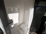 See this bright, compact RV rental bathroom with a toilet, sink, and shower curtain, ideal for travel convenience.