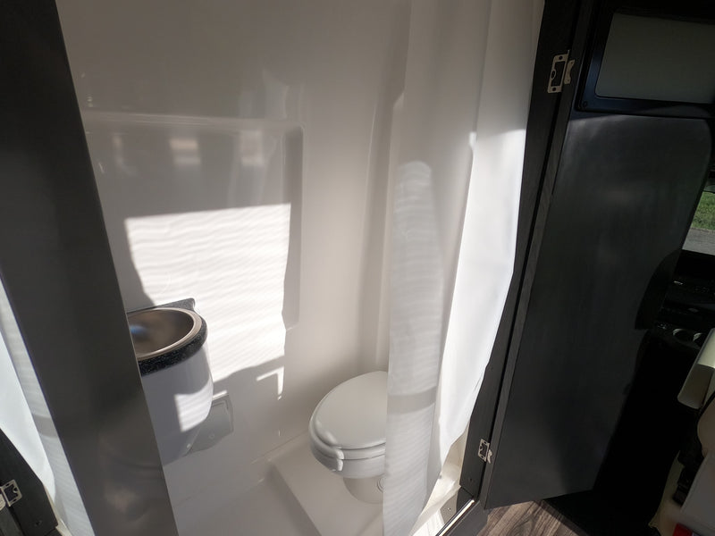 See this bright, compact RV rental bathroom with a toilet, sink, and shower curtain, ideal for travel convenience. — photo 7