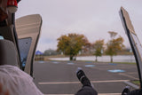 Relaxing inside an RV rental, feet up, enjoying the tranquil lake view and autumn trees from the open back doors.
