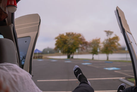 Relaxing inside an RV rental, feet up, enjoying the tranquil lake view and autumn trees from the open back doors.