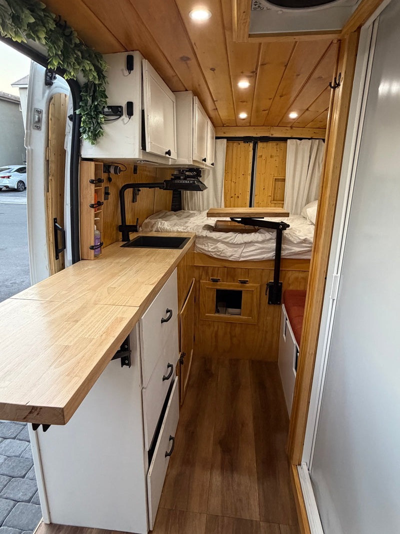 Inside an RV rental: a cozy van interior with a wood-paneled kitchen, bed, and efficient storage for compact living. — photo 5