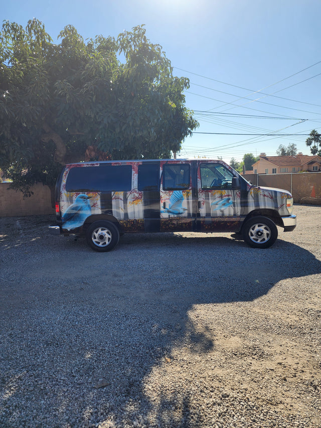 Customized camper van with blue bird art parked on gravel, an ideal RV rental for unique adventures.