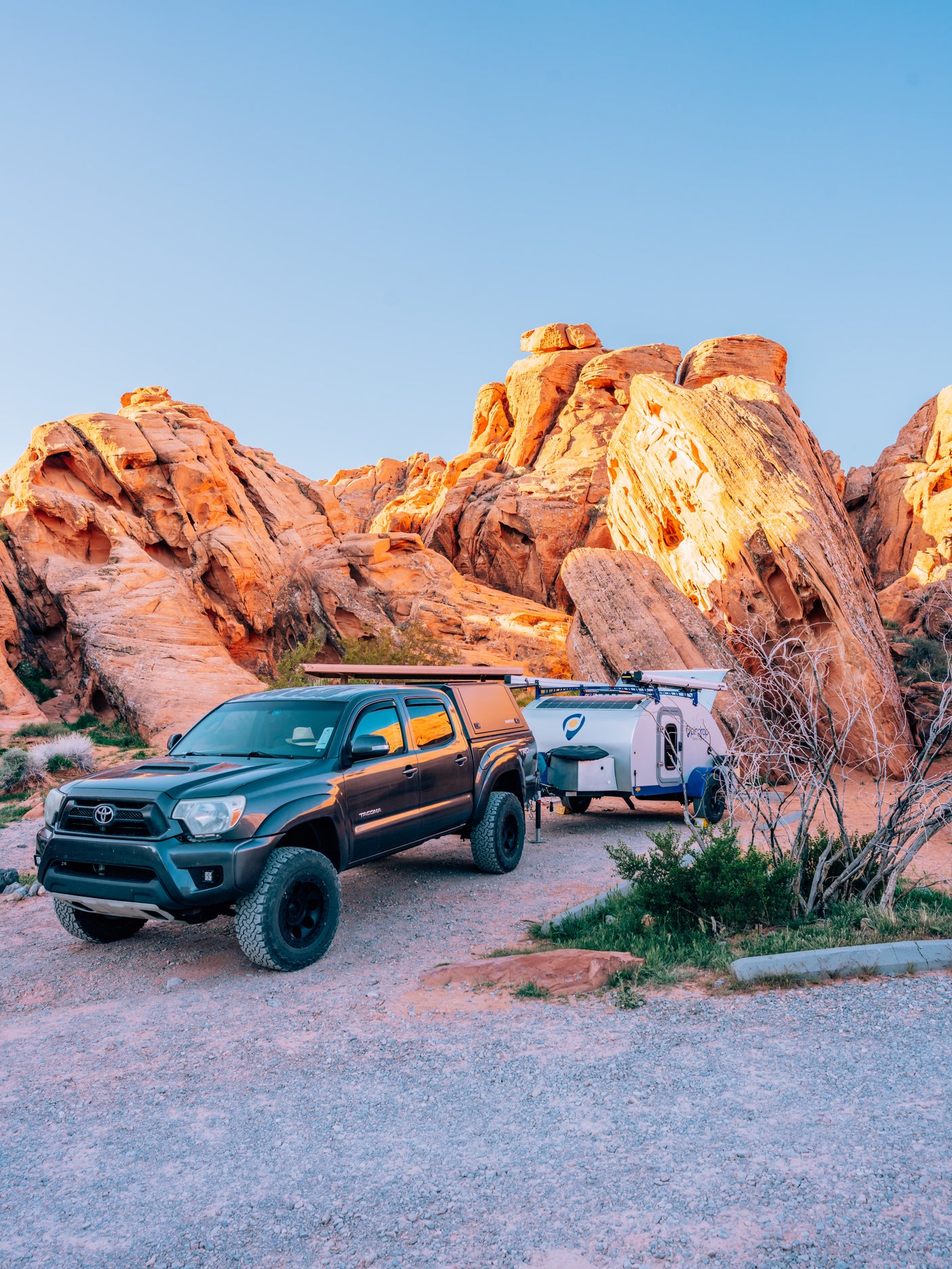 Explore nature's beauty! A Tacoma truck with an RV rental sits amidst majestic red rocks, ready for desert camping.
