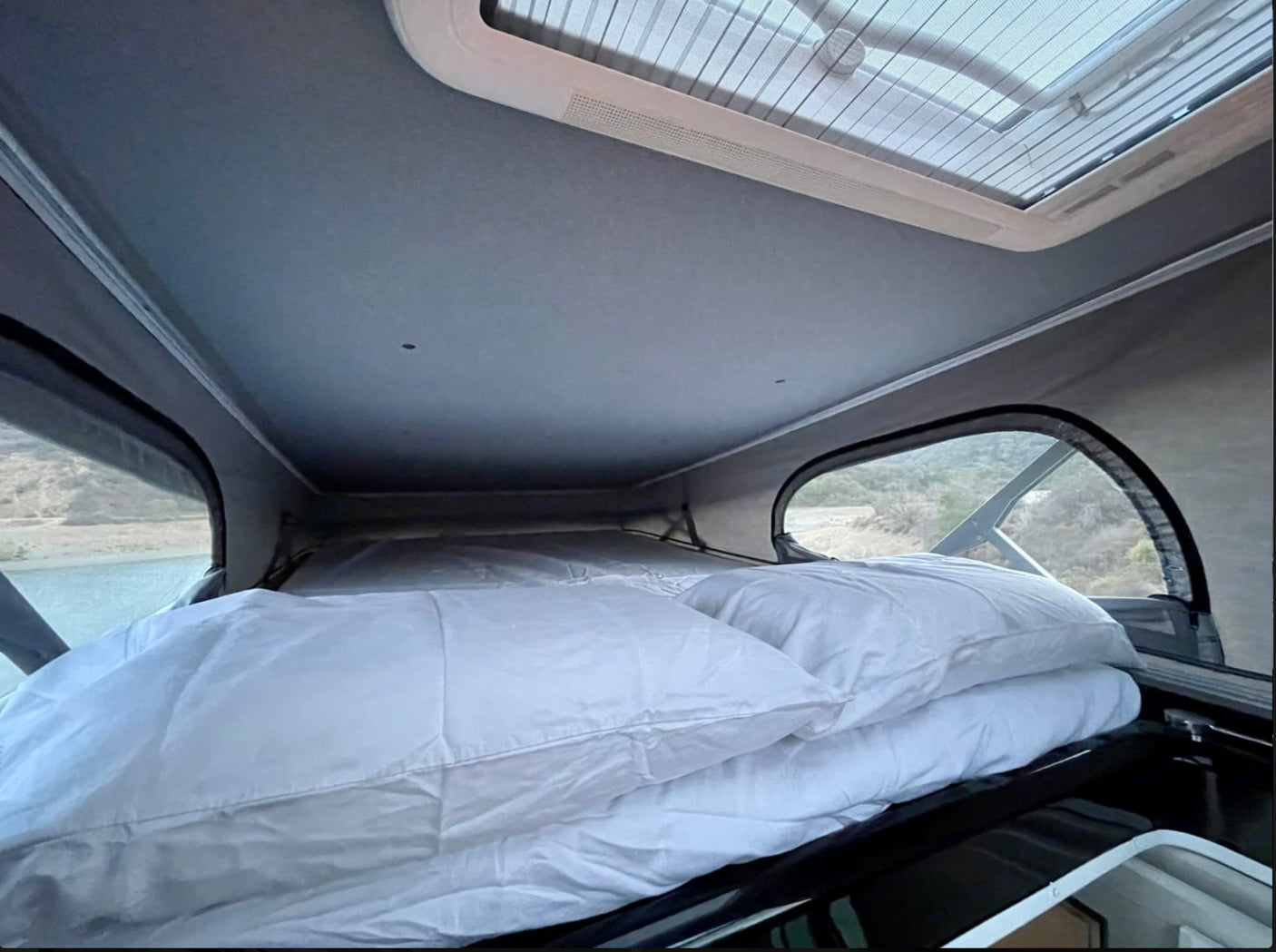  and a window revealing scenic views.|This modern RV rental interior features a compact bathroom with shower & toilet
