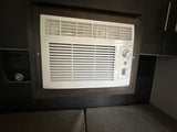 RV rental interior with a compact built-in air conditioner unit, integrated into dark cabinetry for climate control.