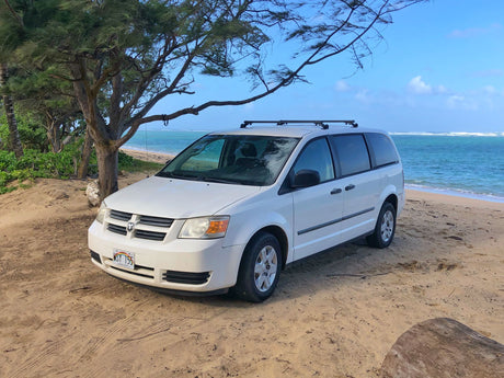 White rental minivan on a Hawaii beach, offering RV rental convenience for island adventures.