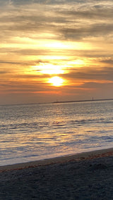 Serene golden sunset over ocean waves & sandy beach. An RV rental escape offers views like this!