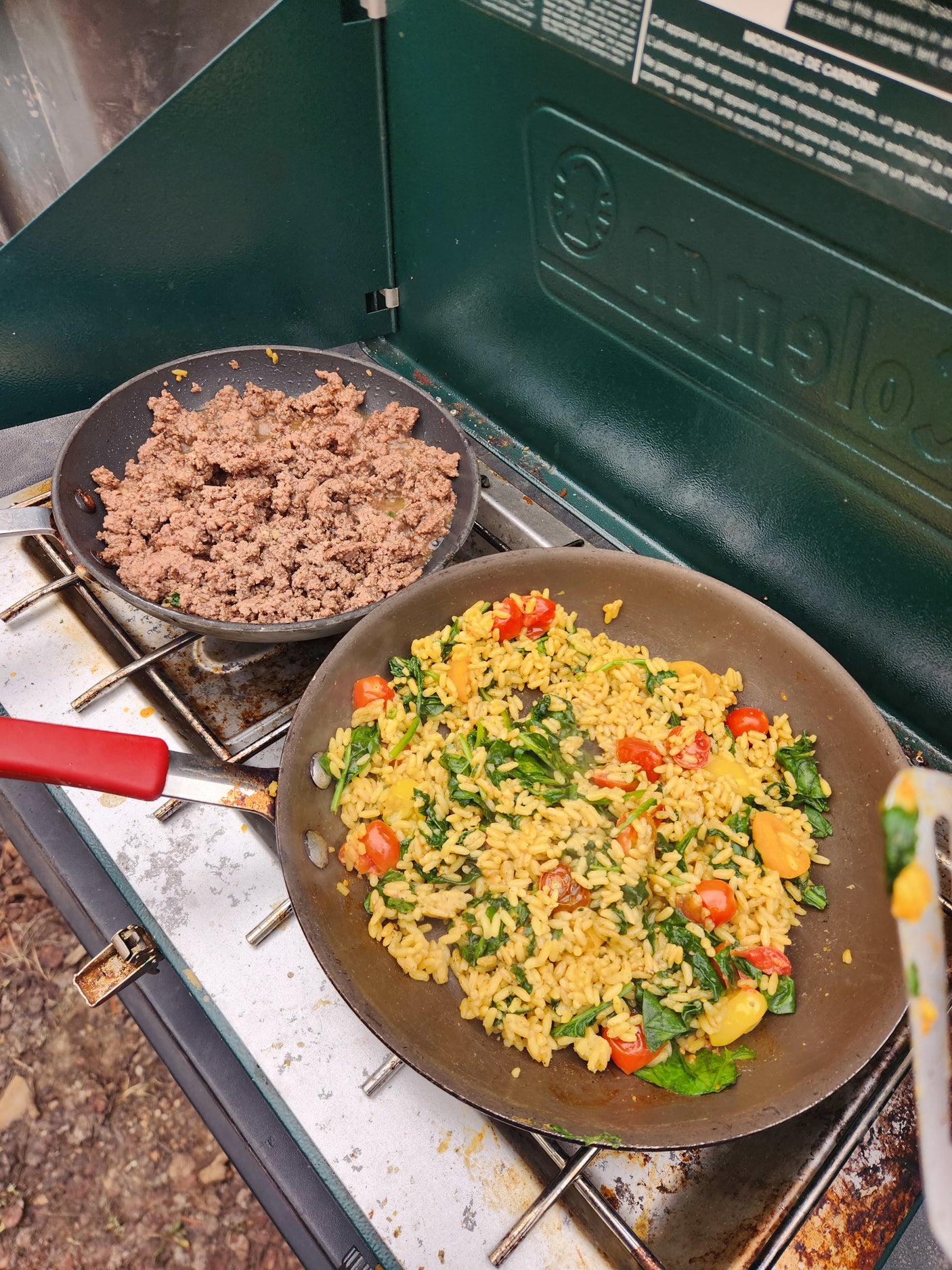 RV rental outdoor cooking: ground meat & a colorful rice skillet with spinach & tomatoes on a portable camping stove.