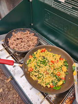 RV rental outdoor cooking: ground meat & a colorful rice skillet with spinach & tomatoes on a portable camping stove.
