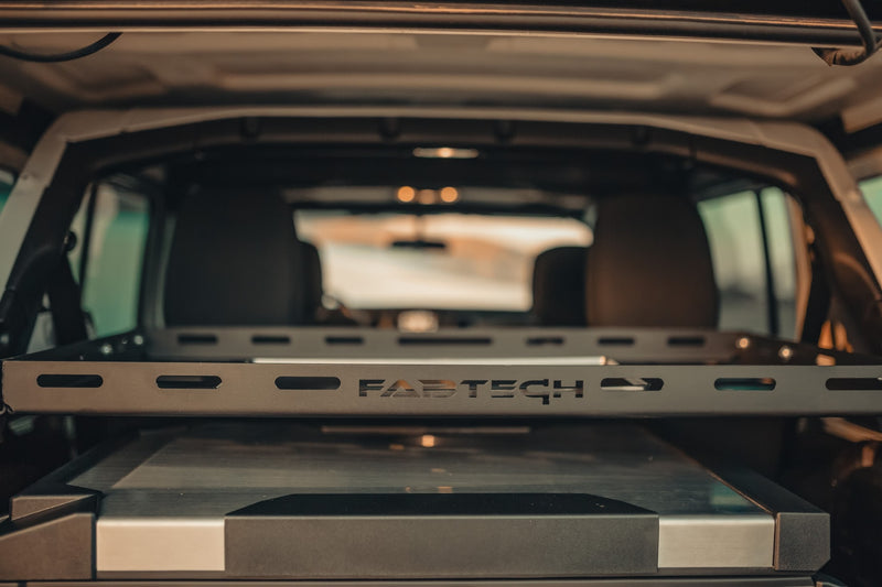 Organized RV rental interior: Fabtech cargo rack above a cooler, ready for adventure. — photo 17