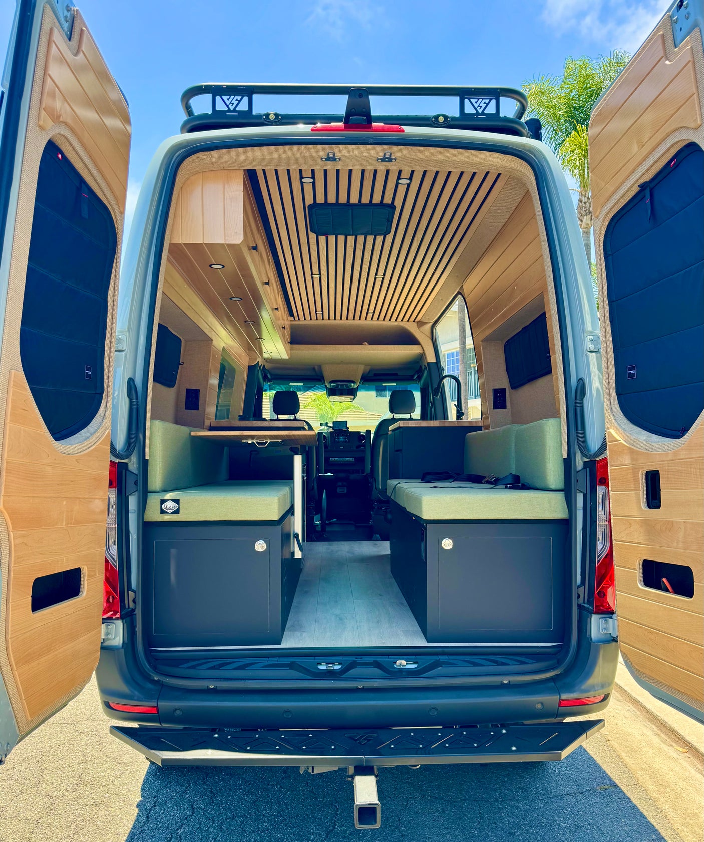 Explore this custom camper van rv rental's modern interior. Features wooden accents, slatted ceiling, and cozy seating.
