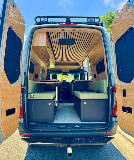 Explore this custom camper van rv rental's modern interior. Features wooden accents, slatted ceiling, and cozy seating.