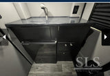 Luxury RV rental van conversion interior: modern kitchenette with sink, integrated fridge, and sleek cabinetry.