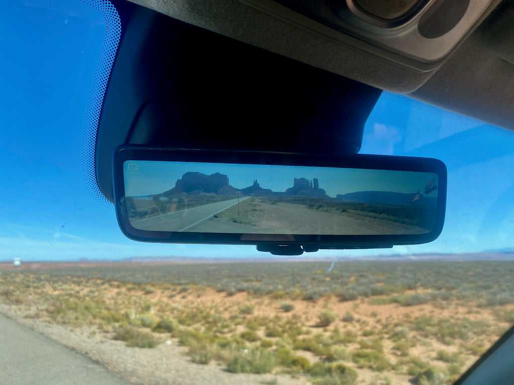 RV rental road trip: Monument Valley vista captured in the digital rearview mirror, showing a desert highway.