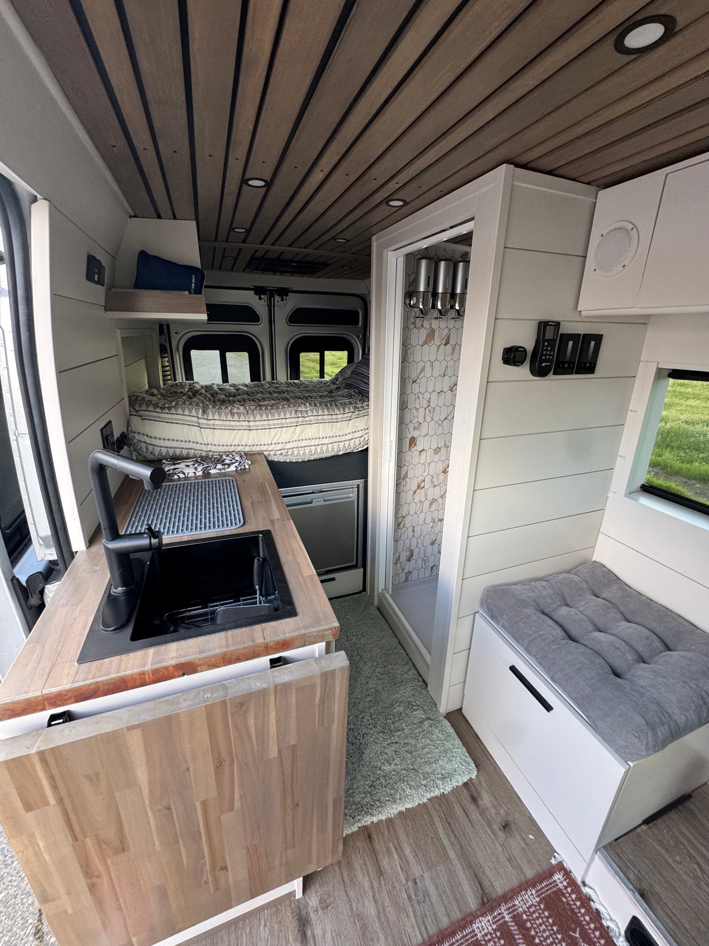 Cozy and functional RV rental interior featuring kitchen, bed, and shower for comfortable travel.