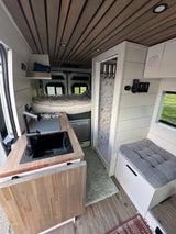 Cozy and functional RV rental interior featuring kitchen, bed, and shower for comfortable travel.