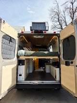 Custom RV rental camper van interior showcasing a comfy bed, storage, and warm wooden ceiling details.