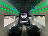 Spacious rv rental interior featuring ambient green LED lighting, a geometric ceiling, plush black seating, and a large entertainment screen.