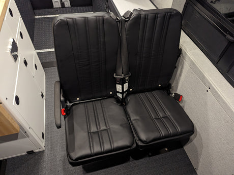 Modular black passenger seats with secure seatbelts on floor rails, ideal for an RV rental.