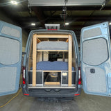 This custom rv rental van conversion reveals bunk beds, pull-out storage, and utilities from its open rear doors.