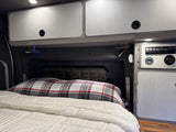 This RV rental's smart interior features a comfortable bed, storage cabinets, and a versatile control panel for power and amenities.