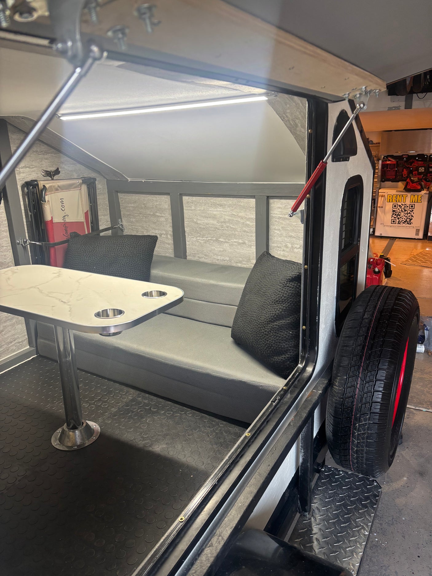 Inside a compact RV rental, showing a dining table with cup holders, bench seating, and rubber floor. Ideal for camping trips.