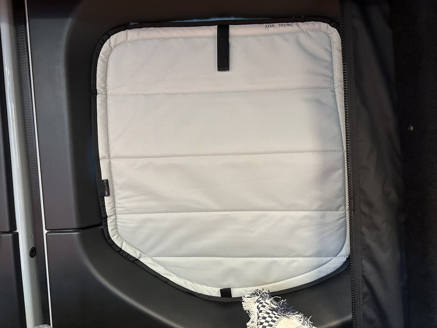 Quilted "REAR DRIVER" window insulation, likely for an RV rental or camper van, improves privacy and climate control.
