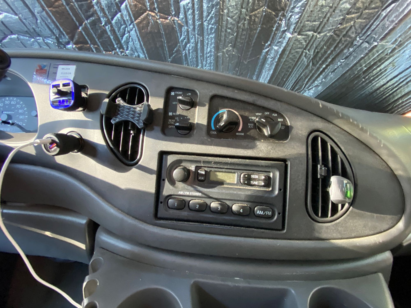  parked on a dirt shoulder against a rugged mountain landscape under a clear sky.|This RV rental shows a converted camper van interior. Note the wood ceiling — photo 6