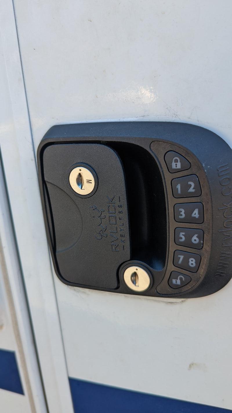 Close-up of an RV rental door with a black digital keypad entry lock, featuring keyholes and numerical buttons for keyless access. — photo 11
