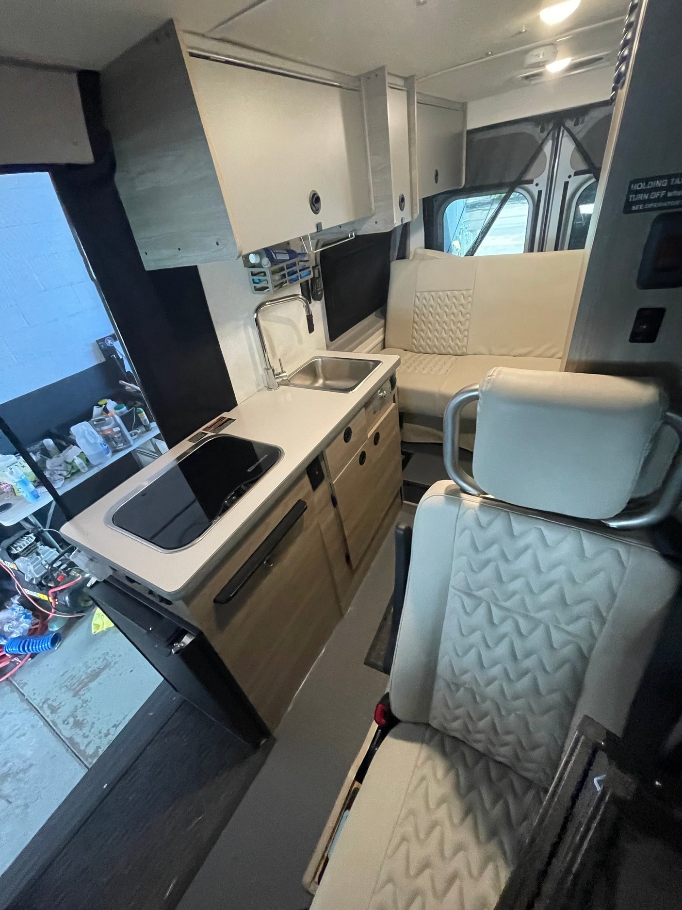 This modern RV rental features a well-equipped kitchenette with sink and cooktop, stylish quilted seating, and intelligent storage design.