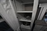 RV rental kitchen cabinet with shelves storing a kettle, pot lids, and pans, plus a hanging rod. Functional storage.